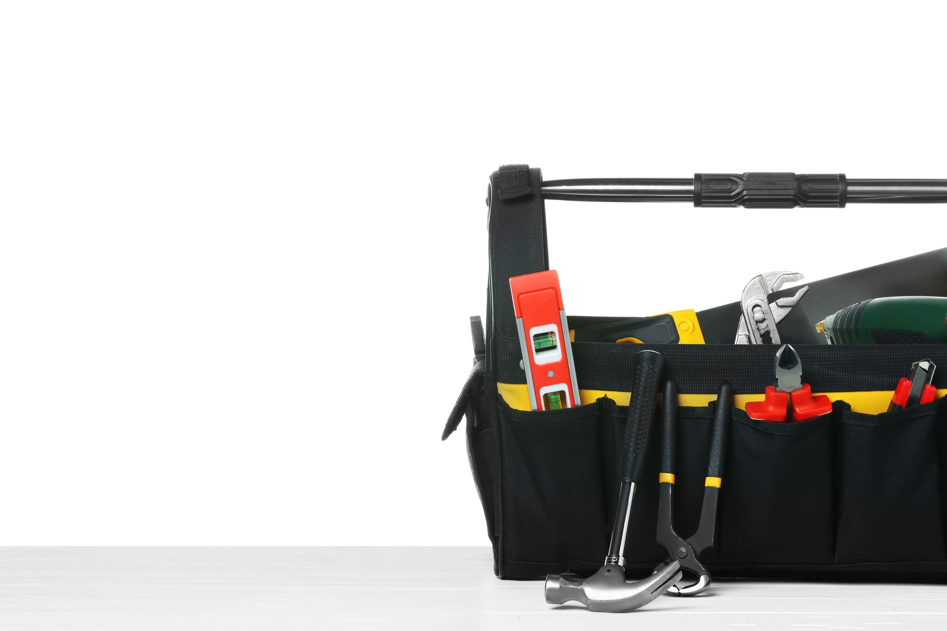 Bag with different tools on wooden table against white background