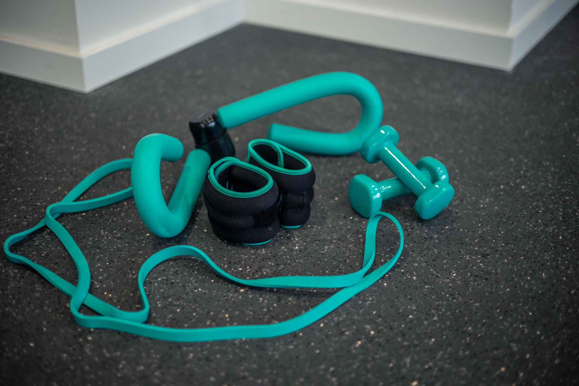 Various gym training equipment such as dumbbells, ankle weights, and resistance bands on gym floor